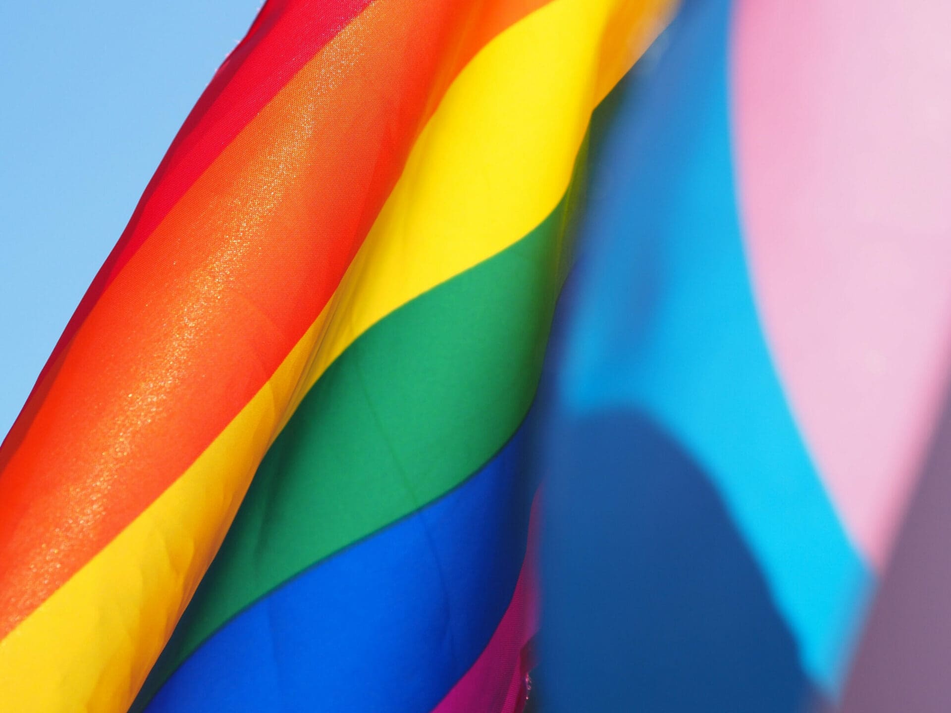 LGBT pride flags against a blue sky