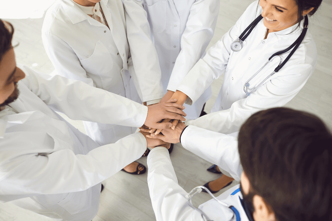 Doctors standing in a circle with their hands in the middle